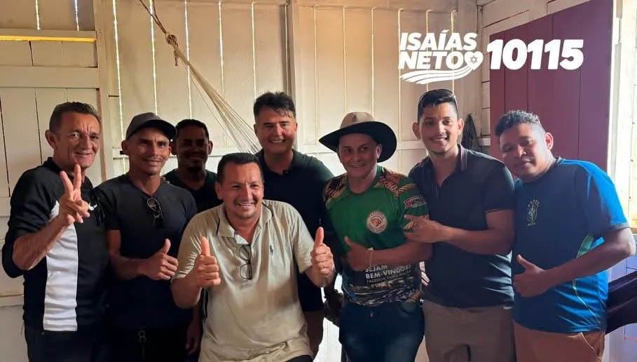 Isaías Neto em roda com um grupo de apoiadores em uma casa de madeira