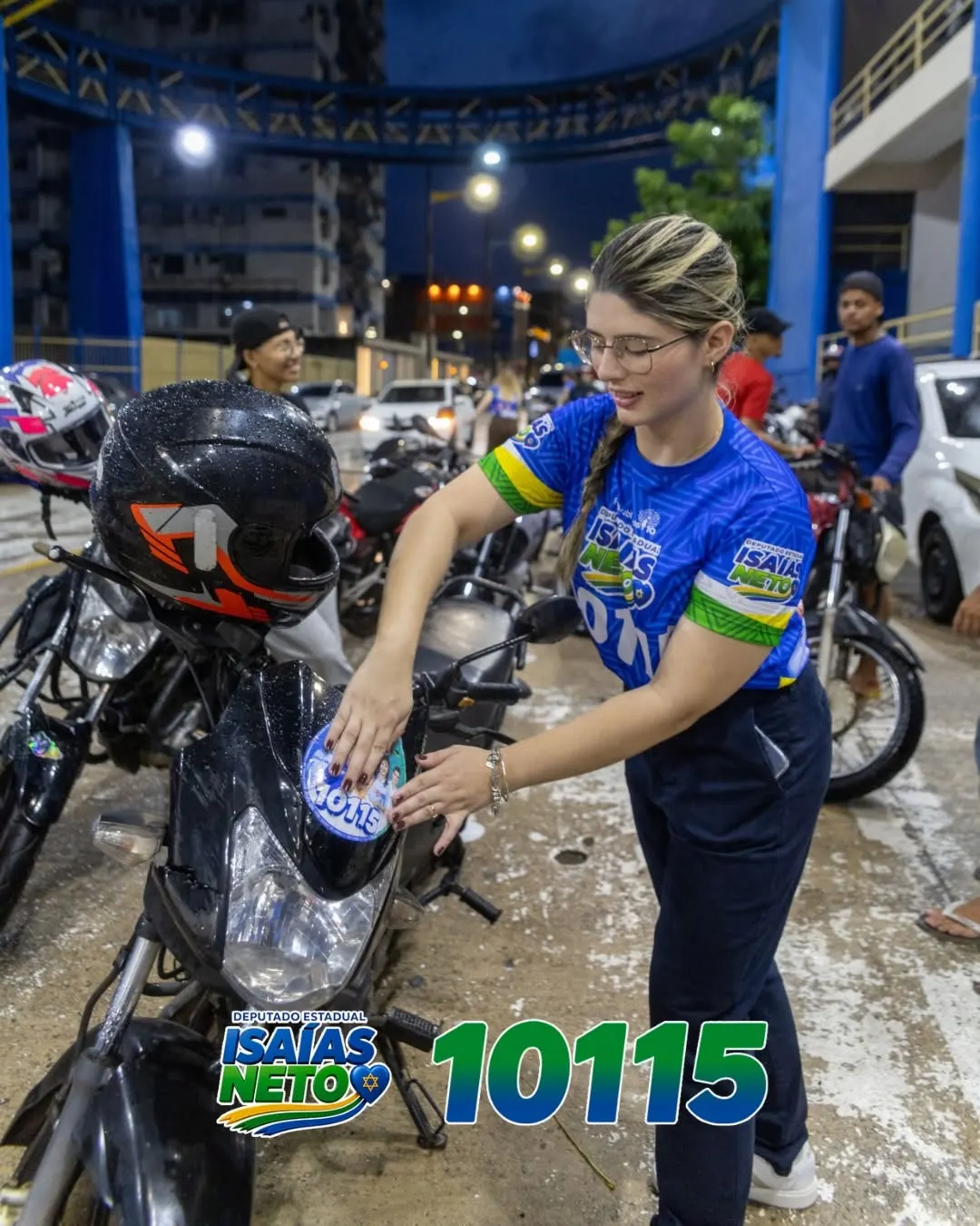 Apoiadora cola o adesivo 10115 no tanque de uma moto durante ação de rua